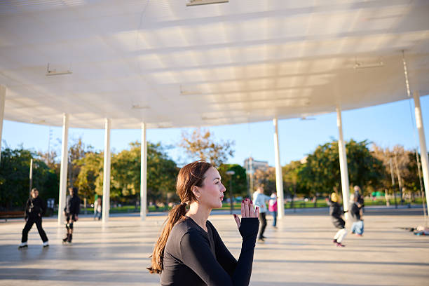 A woman practicing the sun salutation yoga pose outdoors.