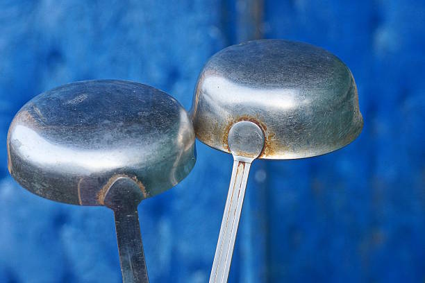 Two gray old metal ladles and spoons on a blue background