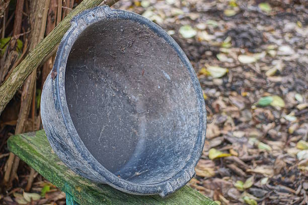 one old black dirty plastic basin stands on a gray wooden table on a rural street