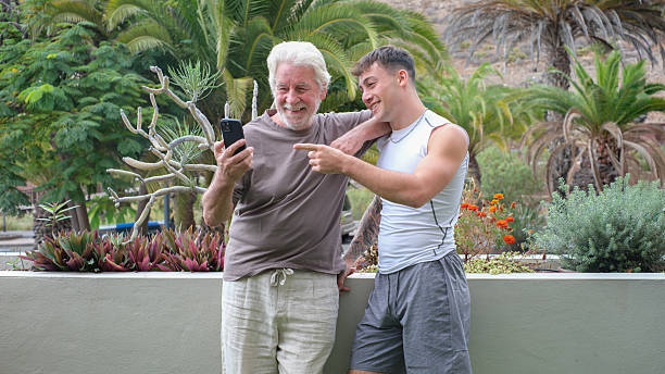 istock Multi generation family, young grandson and old grandfather outdoors on terrace using smartphone sharing social media enjoying stay together in harmony 2248853143