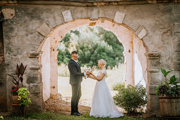 istock Elegant couple exchanging vows in a rustic archway, surrounded by lush greenery and vibrant flowers, capturing the essence of love and commitment in a romantic setting 2248856226