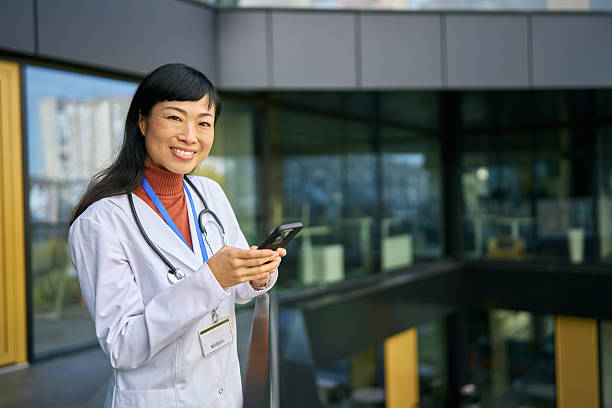 istock Asian doctor smiling using mobile phone at hospital 2248856464