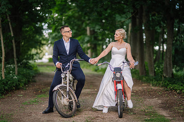 istock Couple in formal attire riding bicycles on a scenic path surrounded by lush greenery, showcasing love and connection in a joyful outdoor setting 2248857394