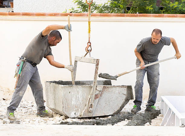 istock Pouring fresh ready-mixed concrete from wheelbarrow on floor during for construction of a house 2248859408
