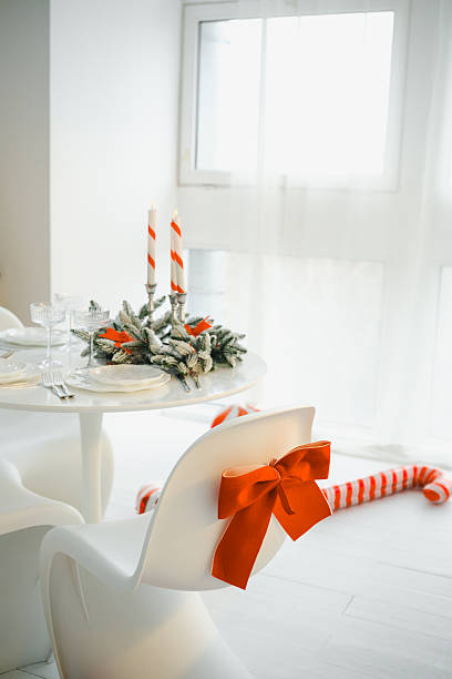 istock Christmas table setting with striped candles and orange bow on white chair with candy cane 2248861574