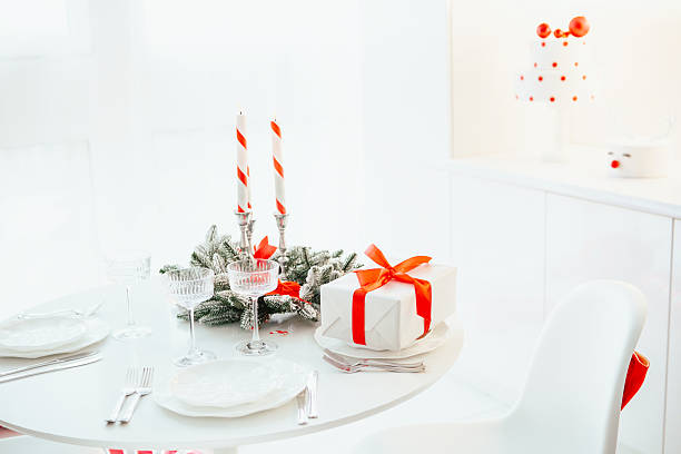 istock Festive table setting with gift box, candles, and elegant glasses on a white surface 2248861585