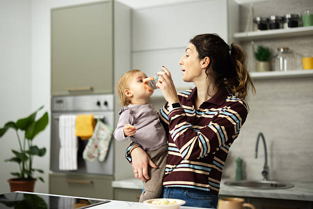 istock Mother feeding baby water bottle in kitchen 2248865968