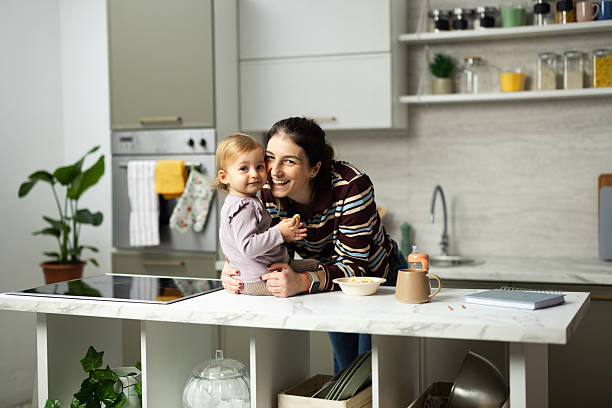 istock Mother and baby daughter cuddling in modern kitchen 2248865989