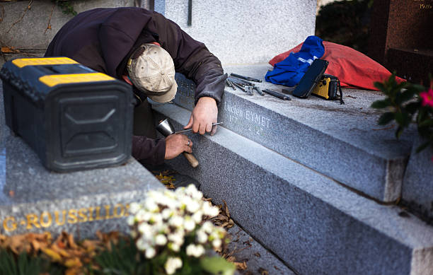 Paris, France: An engraver carving a gravestone in Pere Lachaise Cemetery.