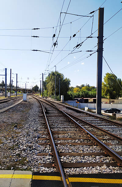 Railway tracks converging into the distance under a bright sky. Illustrates travel, connection, and journeys. Ideal for transportation or metaphorical projects.