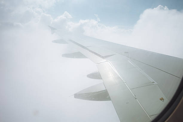 istock View from airplane window with wing above white fluffy clouds and blue sky. g 2248873968