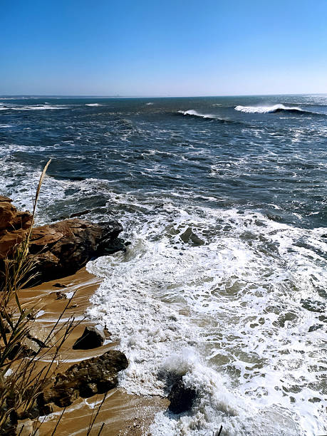 istock Coastal scene with powerful waves crashing onto a sandy beach against a clear blue sky. Evokes serenity and strength. Perfect for travel, nature, or inspirational projects. 2248874302
