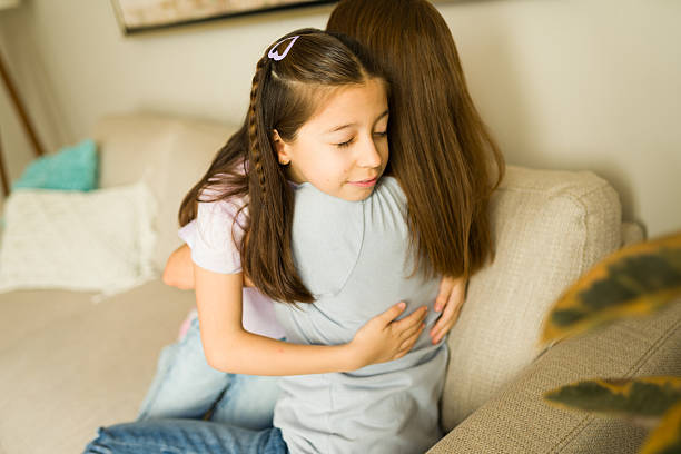 istock Young daughter hugging mother, closing eyes and smiling, feeling comfortable and safe in a warm family cuddle 2248876719