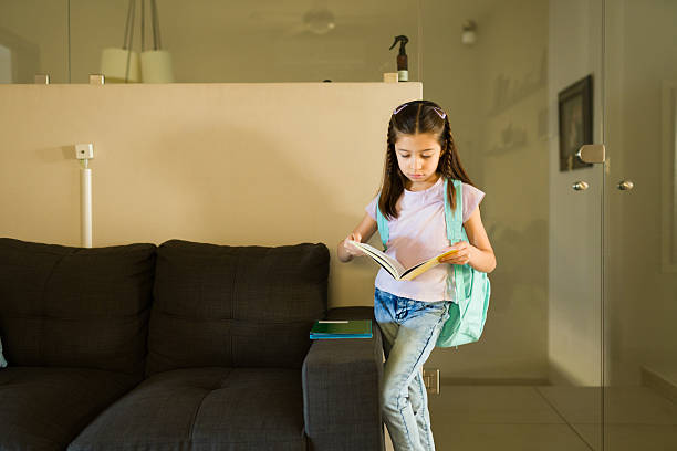 Girl with a backpack reading a book, concentrating on her school homework and studying for academic success