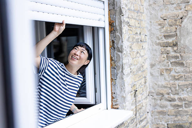 istock Woman opening window roller shutter looking hopeful 2248887823