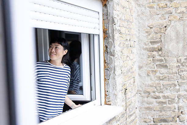 istock Smiling woman looking out window at home 2248887907