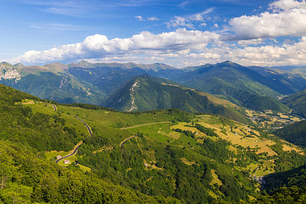 Expansive Pyrenees mountain landscape with a winding road under a bright blue sky