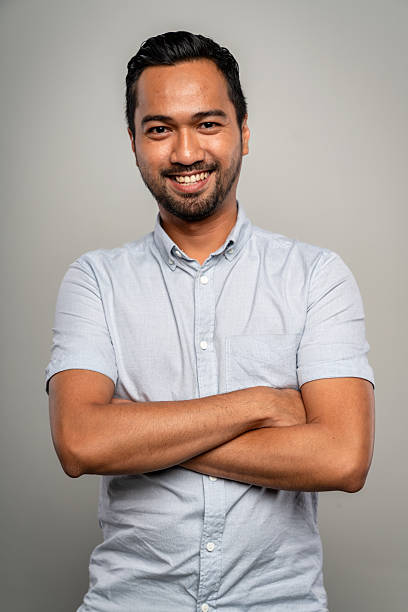istock Smiling Young Asian Man With Folded Arms Standing Confidently In Simple Studio Setting 2248889112