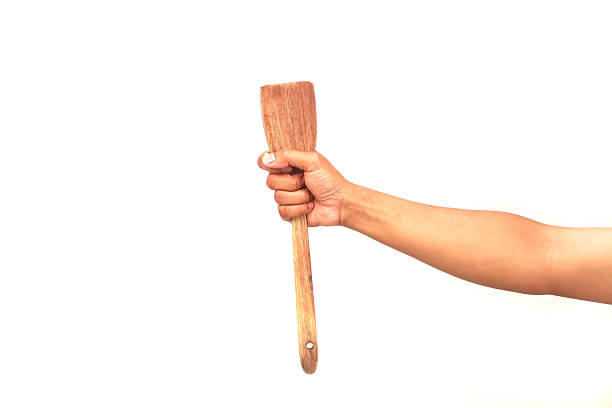 istock A wooden spatula held high by a person's hand on a clean white background creating simple imagery 2248889950