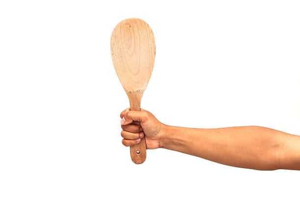 istock Hand holding up a wooden spoon against a plain white background ready to cook 2248889969