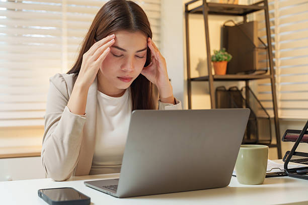 istock Asian female professional suffering from stress holding head while working late using laptop representing mental pressure overwork and fatigue in modern corporate business lifestyle environment 2248890772