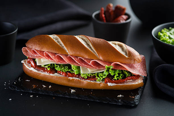 istock Sandwich with salami on black background 2248892055