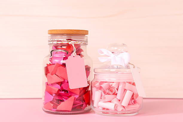 istock Color paper pieces in glass jars on pink table 2248892486