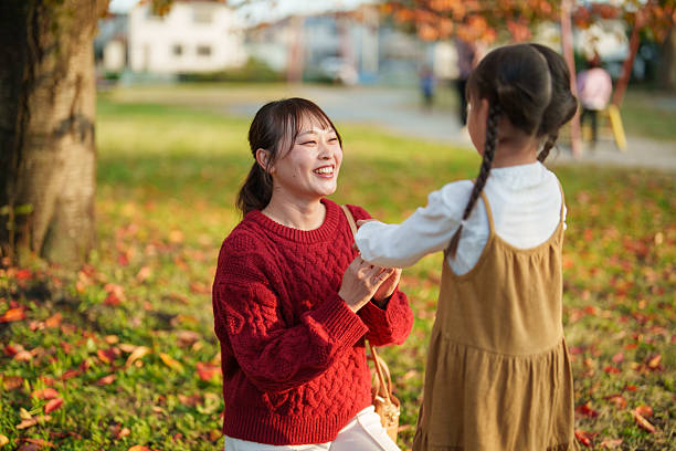 istock Mother Smiling While Holding Hands With Daughter in Autumn Park 2248895118