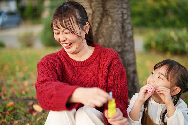 istock Mother Laughing While Sitting With Daughter During Outdoor Playtime 2248896550