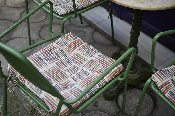 Colorful cushioned chairs surround a table in a cozy outdoor cafe area.