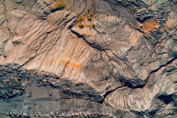 istock Massive sculpted mining waste mound. Aerial abstract of eroded industrial tailings showing complex geological texture in beige, gray, and orange. 2248903455