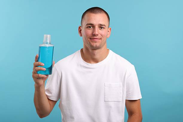 istock Man with bottle of mouthwash on blue background 2248905366