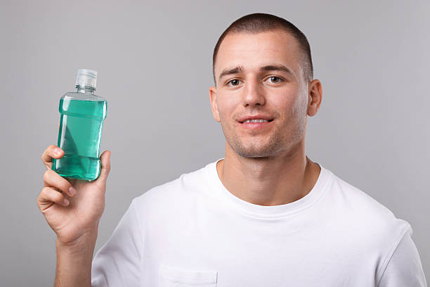 istock Man with bottle of mouthwash on light grey background 2248905401