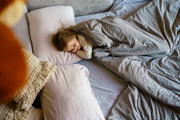 istock Little girl sleeping peacefully in bed with gray blanket 2248905852