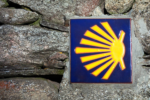 Camino de Santiago, old pilgrimage footpath, pilgrim  sign on stone wall, scallop symbol. Unesco World Heritage site. Año Santo, Camino primitivo, Lugo province, Galicia, Spain.