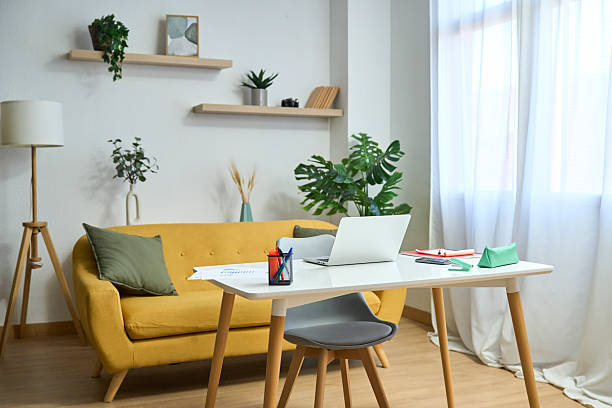 istock Modern home office with desk, laptop, and yellow sofa 2248907175