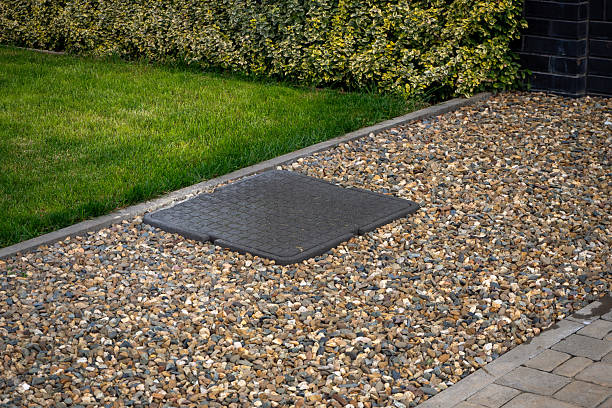 istock Rectangular utility access cover in gravel bed beside green lawn and variegated hedge. Landscape design, property maintenance, hidden infrastructure. Real photo 2248914380