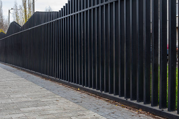 istock Contemporary metal fence with dynamic wave-shaped top line stretching along paved walkway used for residential zoning and modern exterior design. Real photo. 2248914394