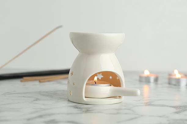 istock Aroma lamp with burning candles and incense on white marble table, closeup 2248915153