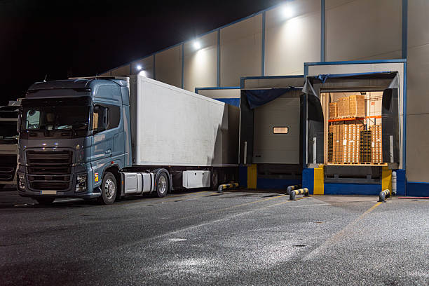 istock Several loading docks with trucks backed up and an open dock door showing palletized goods 2248918591