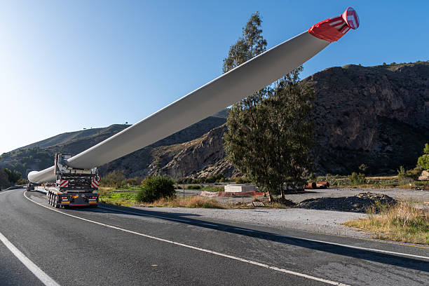 Wind turbine blade transported on a flatbed truck along a conventional road.