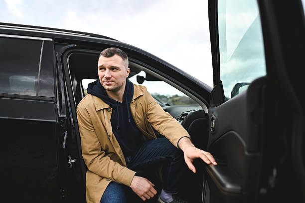 Man getting out of a car, pausing to look away