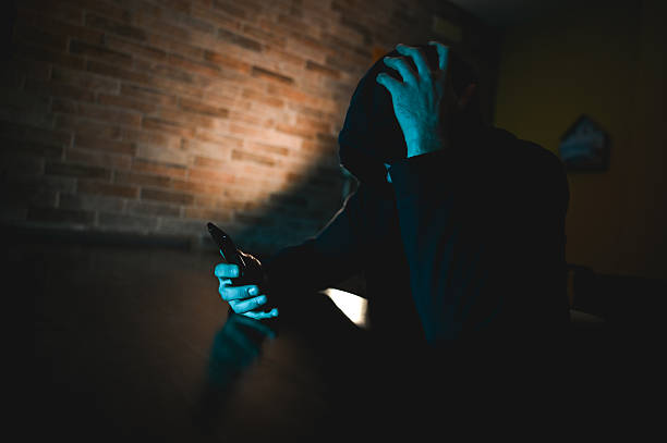 istock Stressed person holding phone in dimly lit room 2248919794