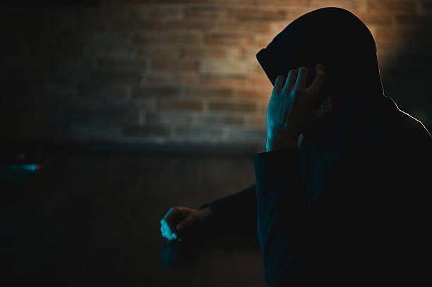 istock Hooded figure holding phone in dark urban setting 2248919811