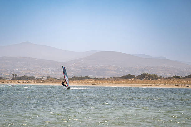A windsurfer glides across a windy lagoon with rugged hills in the background on Naxos, Greece, capturing the island’s active seaside atmosphere and natural beauty.