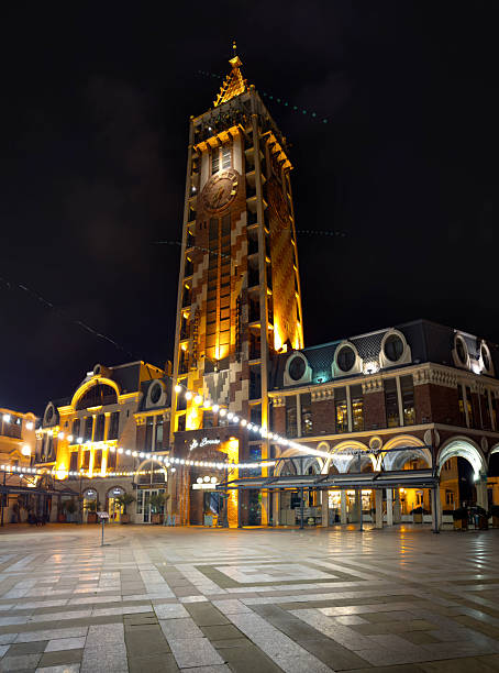 A nighttime view of the historic Halifax Town Clock in Nova Scotia, Canada. The white, domed structure stands prominently on a grassy hill, softly illuminated against the dark sky. Its classic Georgian architecture and glowing clock faces evoke a sense of timelessness and quiet elegance. A metal fence lines the foreground, adding depth to the serene urban scene.