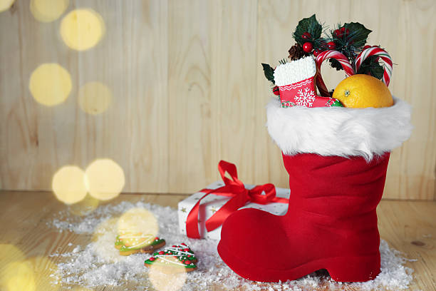 istock Saint Nicholas day tradition. Red boot with sweets, festive decor, gift box and artificial snow on wooden table 2248927101