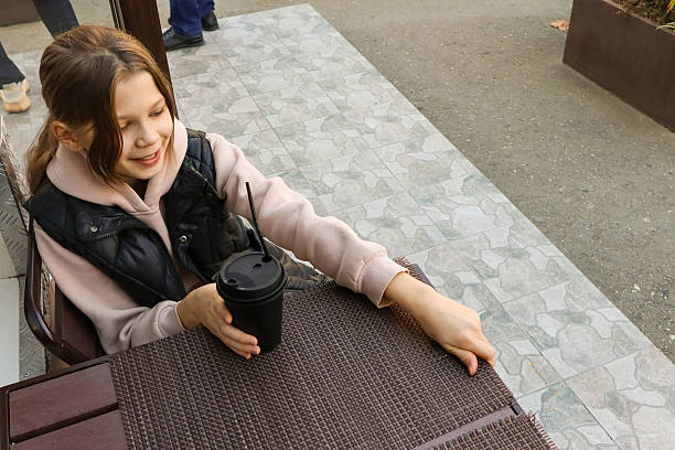 Teenage girl placing hand near coffee cup on cafe table