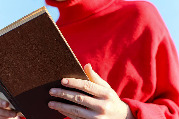 istock Woman reading book with blue sky backdrop 2248932893