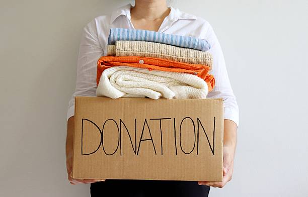 istock Woman holding cardboard box with second hand clothes and 